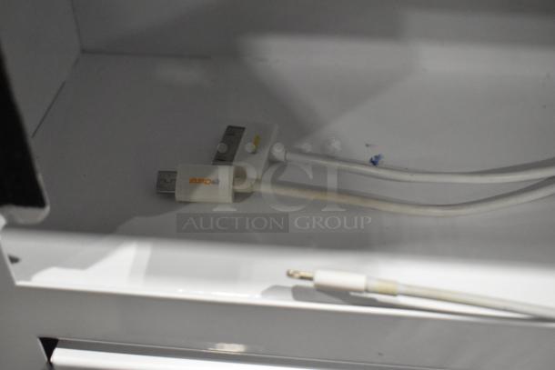 Metal 10 cubby filing cabinet with combination lock, used condition, includes visible white charging cables within a cubby.