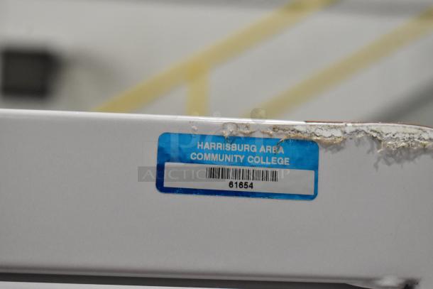 Metal 10 cubby filing cabinet with combination locks, label from Harrisburg Area Community College, item number 81654 shown.