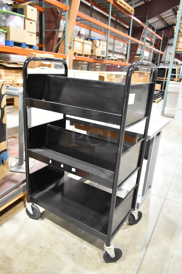 Black 3-tier cart on casters, sturdy metal design, shown in warehouse. Part of auction lot with gray desk.
