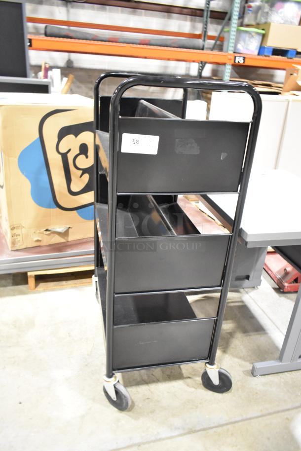 Black 3-tier metal cart on casters, with a labeled sticker, alongside a gray desk, used condition.
