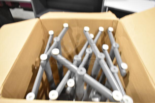 Box containing multiple grey metal table legs with white caps, part of a 2 pallet set including tabletops.