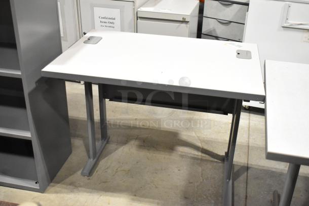 Three items including a gray bookshelf and two desks, all in good condition. Desks feature cable grommets.