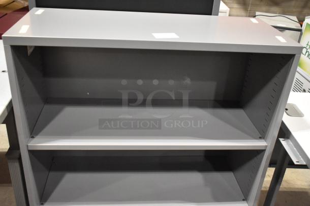 Gray metal bookshelf, two adjustable shelves, excellent condition, ideal for home or office storage.