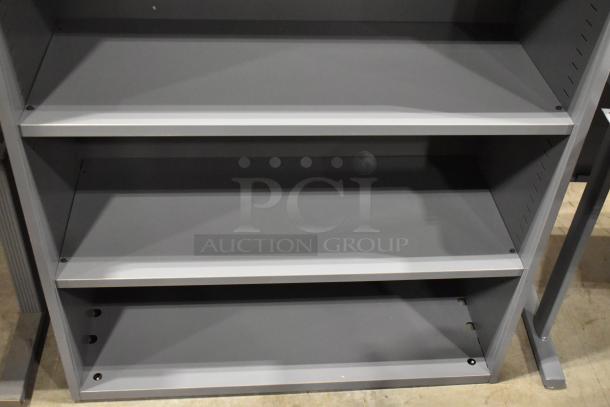 Gray metal book shelves with adjustable shelves, sturdy design, some wear visible, perfect for office or home use.
