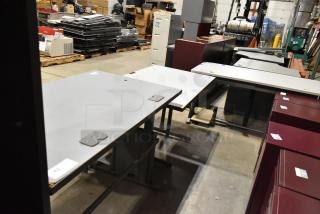 Three various gray desks in used condition, featuring flat tops and cable management grommets. Auction lot includes all three.