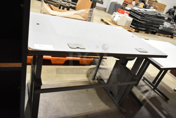 Three gray desks, metal frames, slight wear on surfaces, label with number "63" visible. Auction includes three desks.