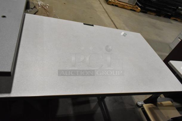 Three gray desks, rectangular shape, shown with smooth surfaces and metal legs. Minimal wear, ideal for office use.