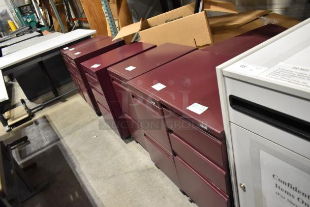 Six maroon metal filing cabinets, including 2-drawer and 3-drawer units, in good condition. Auction offers six times your bid.