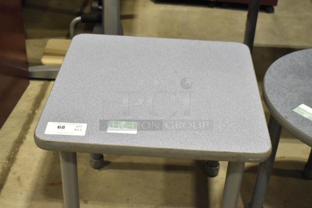 Two gray end tables: one square, one round. Metal legs, textured surface. Tags show auction details. Slight wear visible.