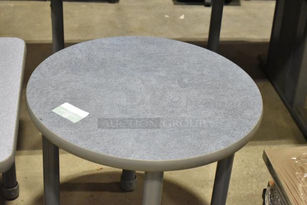 Two gray end tables, one square, one round, in good condition. Each has a durable finish and sturdy legs. Auction tag visible.