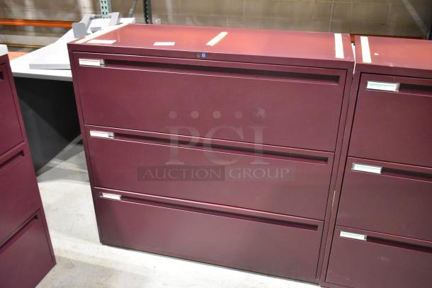 Maroon metal 3-drawer filing cabinet, sturdy design. Slight scratches visible, label holders on each drawer.