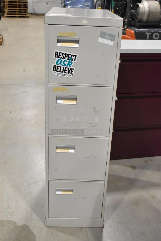 Gray metal four-drawer filing cabinet with stickers, visible wear, and scratches, ideal for office storage.