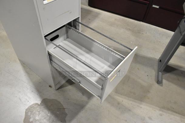 Gray metal 4-drawer filing cabinet, open drawer, minor wear, sturdy construction, suitable for office storage.
