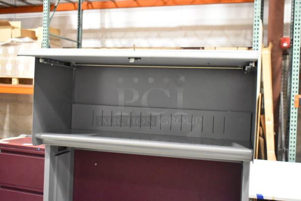 Gray desk with overhead cabinet, metal construction, integrated slotted back panel, excellent condition.