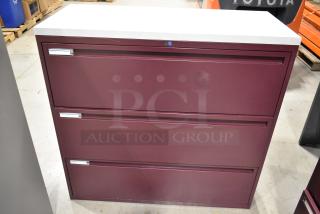 Maroon metal 3-drawer filing cabinet with silver handles, in good condition. Features lockable top drawer and label holders.