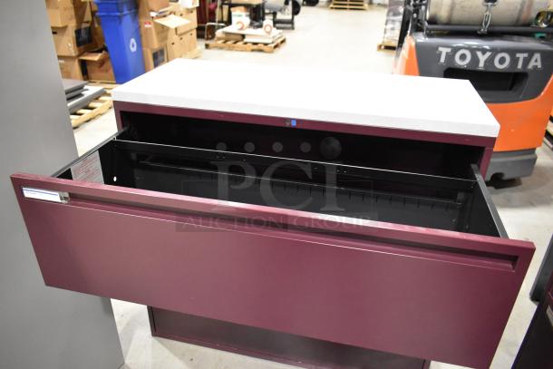Maroon metal 3 drawer filing cabinet, open drawer, good condition, no visible markings or labels, ideal for office use.