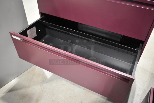 Maroon metal 3-drawer filing cabinet in good condition; open drawer shows spacious interior with label inside.