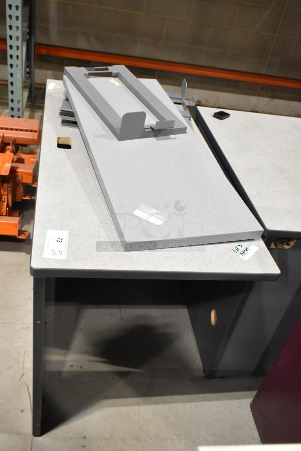 Three gray desk pieces in used condition, featuring varied shapes and sizes. Includes visible auction tags and labels. Ideal for office use.