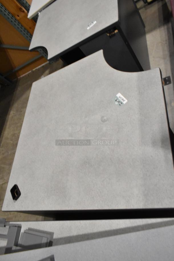 Three gray desk pieces with curved edges, shown in warehouse. Labels indicate auction item. Good condition.