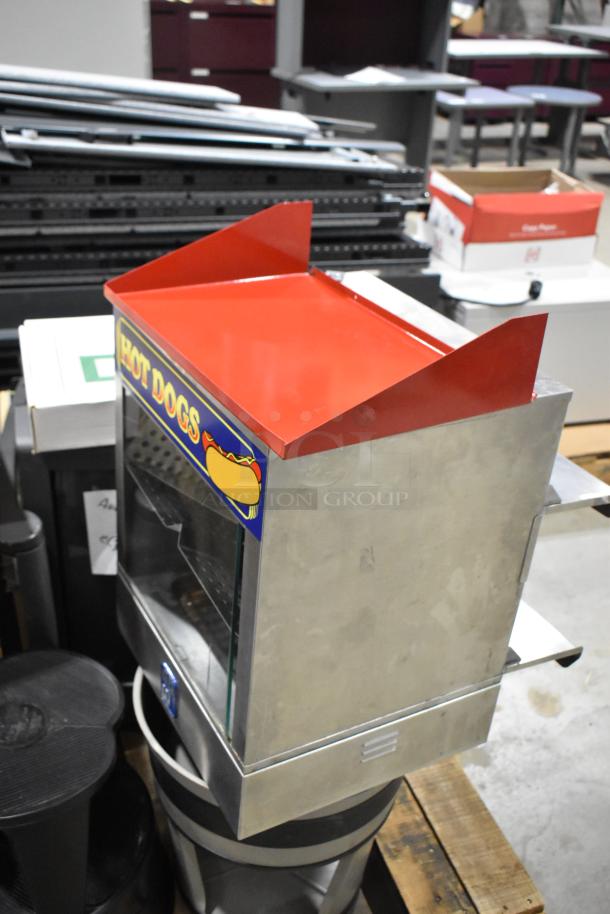 Pallet lot with a metal hot dog merchandiser, featuring a red top and "HOT DOGS" sign, among various items like stools and a TV.