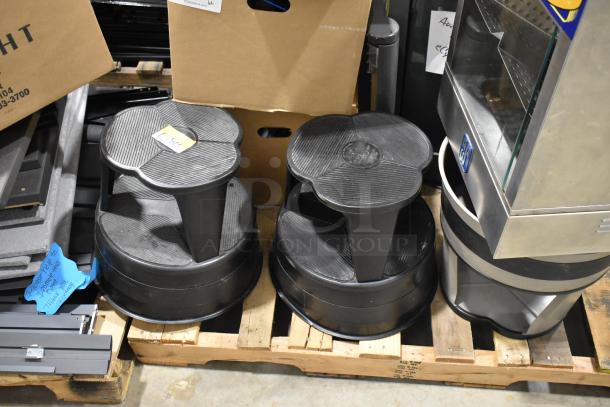 Pallet with various items including two black stools, metal hot dog merchandiser, and cardboard boxes in warehouse setting.