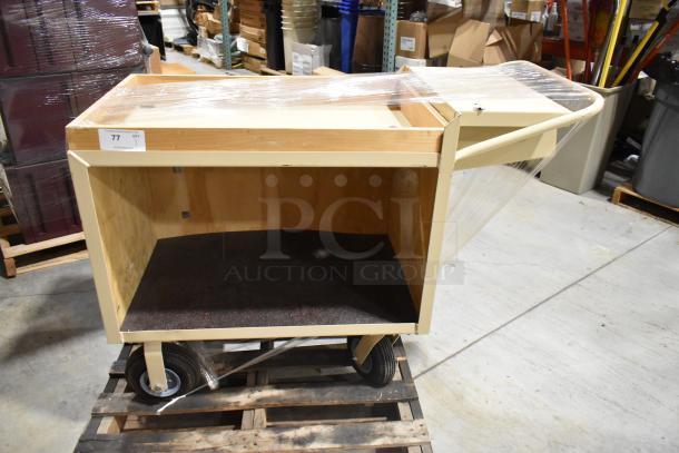 2 tier cart on casters, wooden frame, beige finish, good condition. Features handle and wheels for easy mobility. Item tag 77.