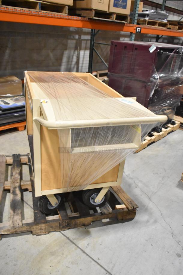 2-tier cart on casters, wrapped in plastic, yellow frame, large wheels, sturdy construction, suitable for warehouse use.