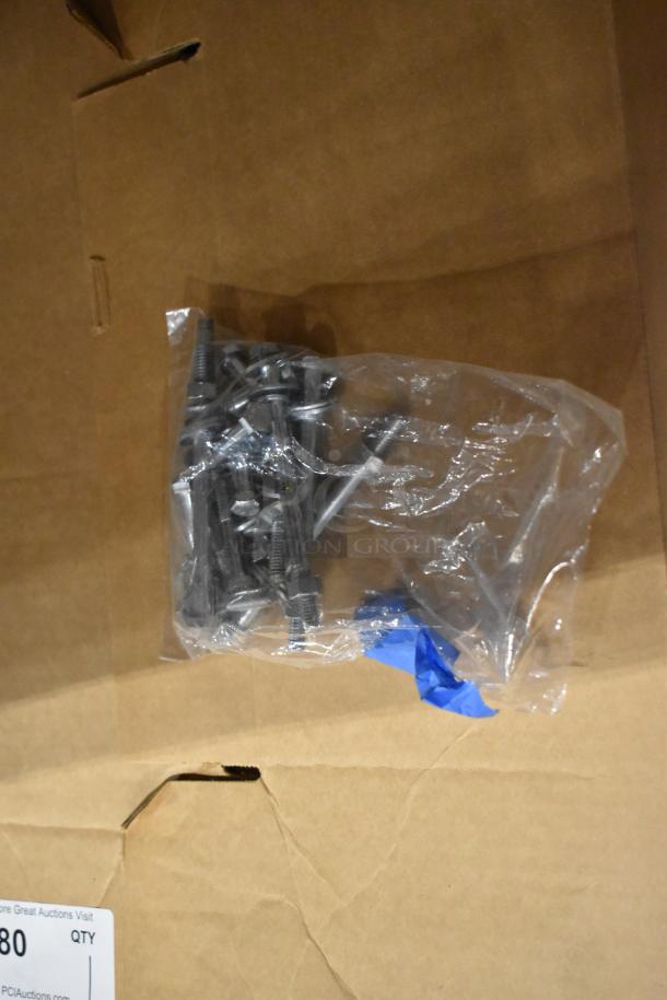 Bag of metal bolts on shredded cardboard, part of a mixed pallet lot. Includes various panels and metal pieces. Condition undetermined.