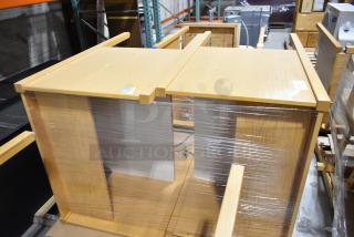 Two wood-pattern desks, wrapped in plastic, new condition, light wood finish, auction stickers visible on top surfaces.