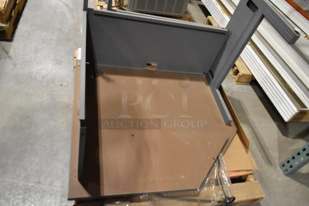 Two gray desk pieces in used condition, showing a partially assembled structure with metal frames and brown panels. No visible markings.