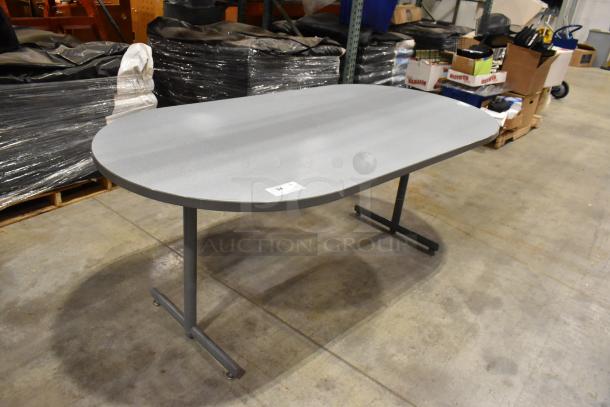 Gray oval table with metal legs, in good condition. Ideal for office or home use. Label reads "94."
