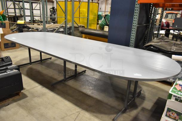 Gray oval table with a smooth surface and sturdy metal legs, suitable for conference or dining use, in good condition.
