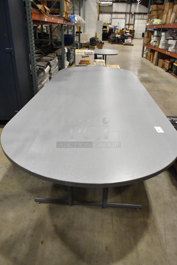 Gray oval table with a smooth surface, metal T-shaped legs, in excellent condition, suitable for conference rooms.