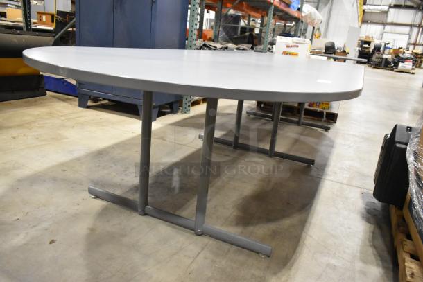 Gray oval table with metal legs in good condition. Suitable for office or conference use. No visible labels or tags.