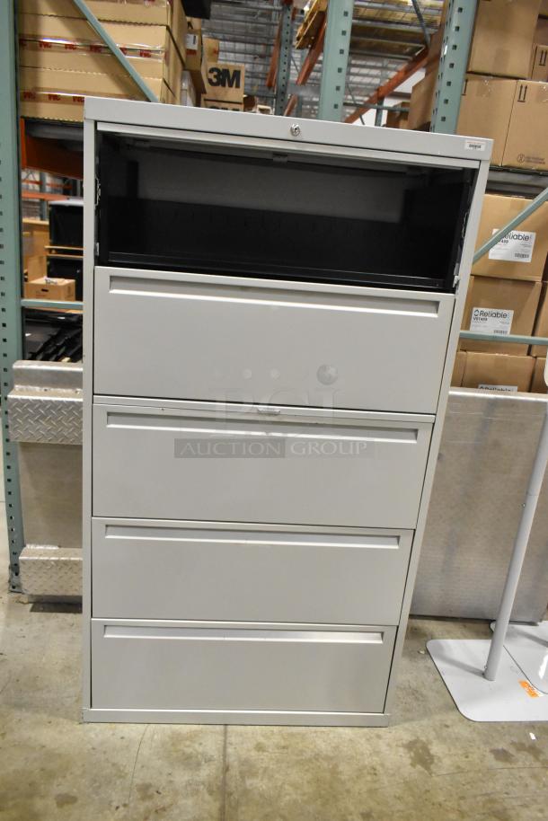 Gray metal filing cabinet with 4 drawers and 1 door, secure lock, minor wear, durable construction, ideal for office storage.
