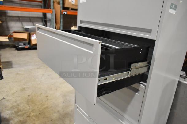 Gray metal filing cabinet with four drawers and one door, open drawer shown. Good condition, industrial setting.