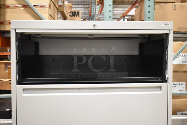 Gray metal filing cabinet with four drawers and one door, open top compartment, secure lock, good condition.