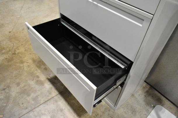 Gray metal filing cabinet with four drawers and one door. Features smooth-sliding mechanism; excellent condition.