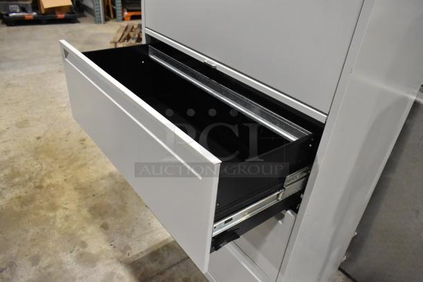 Gray metal filing cabinet with four drawers and one door, one drawer open. In good condition, sturdy construction.