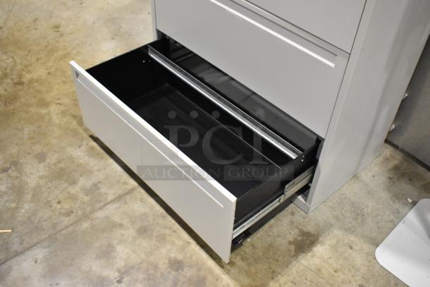 Gray metal filing cabinet with four drawers and one door, featuring a smooth finish and sturdy construction. Open drawer shown.