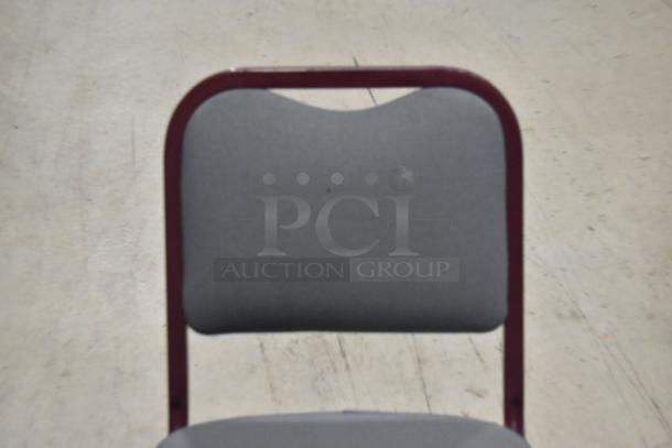 22 maroon metal chairs with gray seat and backrest, sold together. Durable, stackable, good condition.