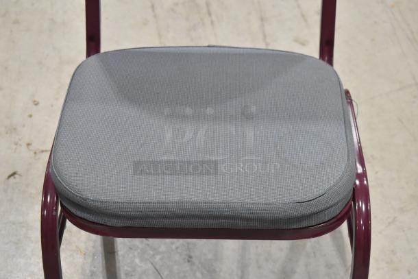 Maroon metal chair with gray seat and backrest, gently used, stackable design. Auction lot: 22 chairs total.