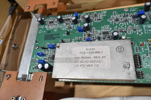 Close-up of a PCB assembly inside a Signature Series wooden table with electronics. Label reads "R3520 PCB Assembly, P/N 282949, REV 02."