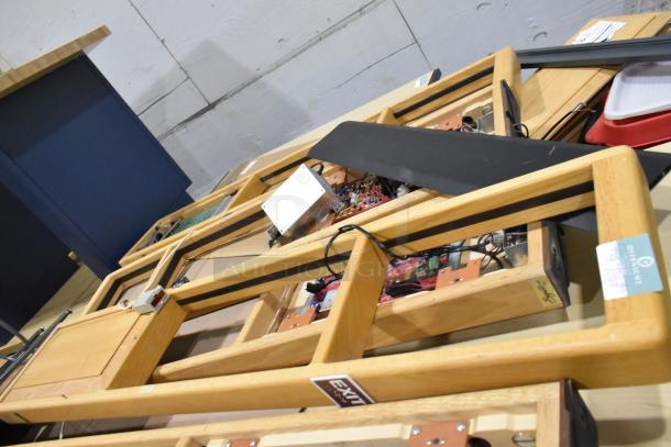 Five Signature Series wooden tables with integrated electronics, showing intricate wiring and build. Each frame includes tags with branding and model details, indicating authenticity and value.