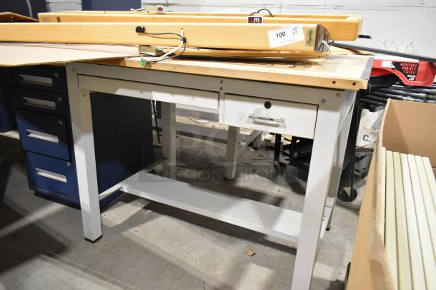 Gray metal table with wooden tabletop, featuring storage drawers. Slight wear, sturdy, ideal for workshop or garage use.