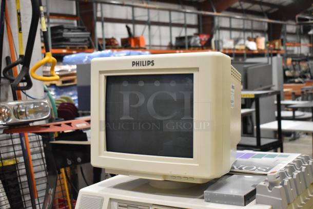 Philips M2424A Ultrasound System with CRT monitor, on casters, in used condition; visible control panel and paper holder.