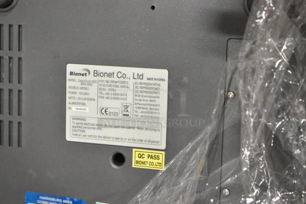 Bionet CardioTouch-3000 label showing model, serial number, and QC pass sticker on the device surface.
