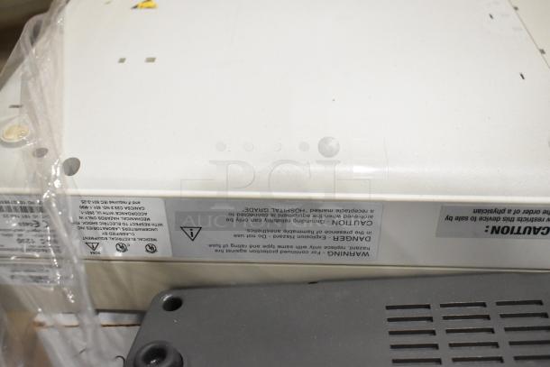 Pallet of various medical items including Bionet CardioTouch-3000 ECG and GE Medical MAC1200 EKG machine. Labels warn hospital-grade use.