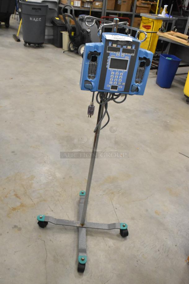 Alaris Signature Edition infusion system on caster stand, with control panel and power cord, used condition in warehouse setting.