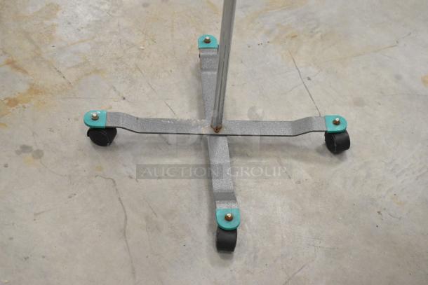 Base of medical stand on casters with teal accents, suitable for Alaris Infusion System. Visible wear and rust on metal surface.